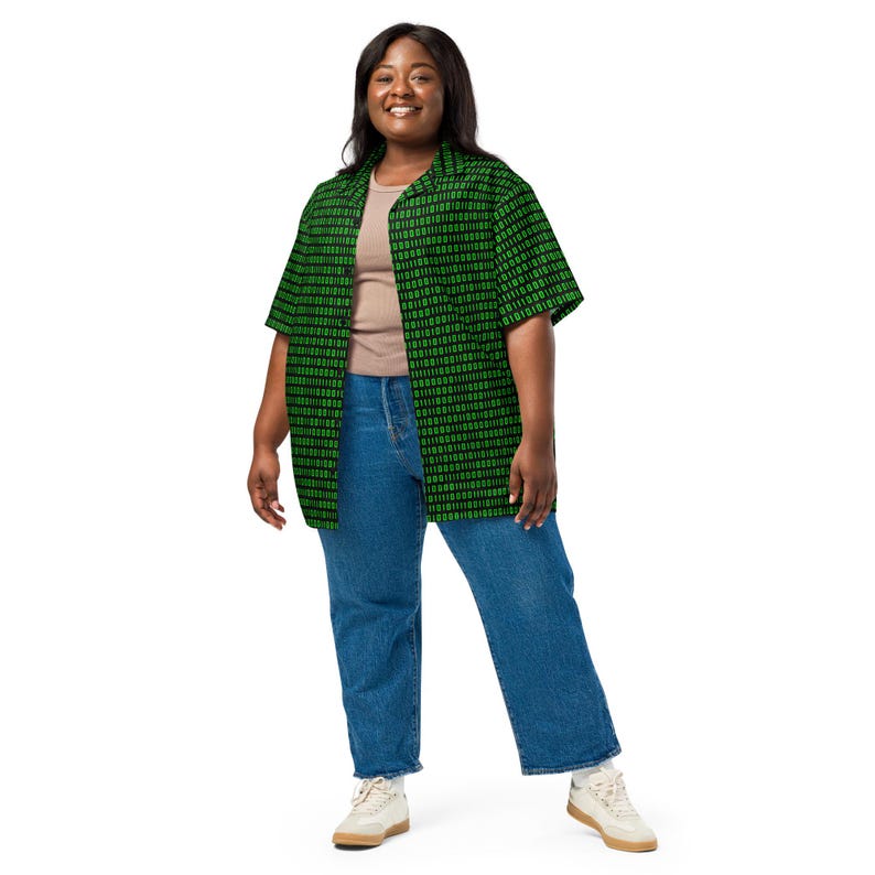Puede incluir: Una camisa de manga corta con botones y un patr&oacute;n de c&oacute;digo binario en negro y verde, usada sobre una camiseta sin mangas color canela con jeans azules y zapatillas blancas. La camisa tiene cuello cl&aacute;sico y dobladillo recto digital.