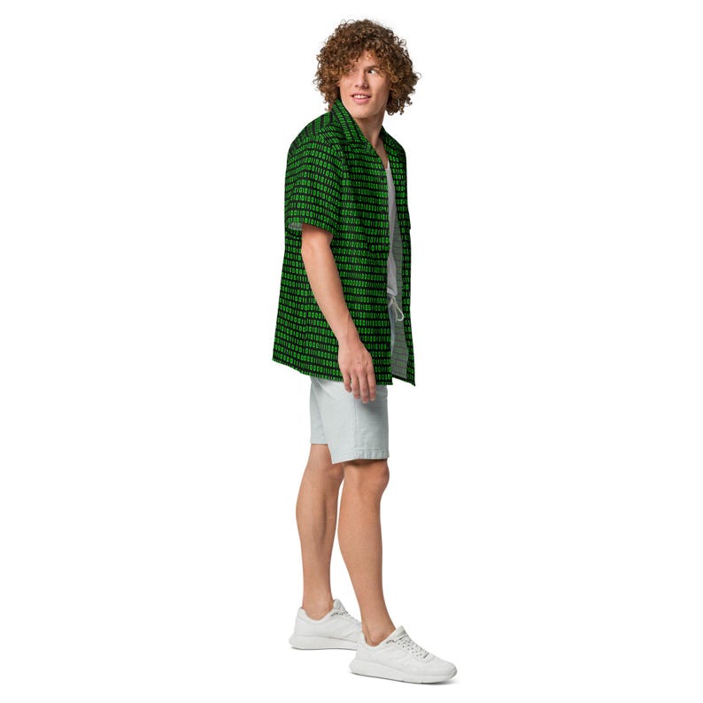 Puede incluir: Una camisa de manga corta con botones, fondo negro y un patr&oacute;n repetitivo de c&oacute;digo binario en verde, usada sobre una camiseta sin mangas gris claro con pantalones cortos gris claro y zapatillas deportivas blancas, vista de perfil.
