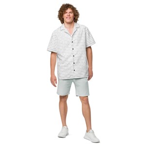 May include: A short-sleeved button-down shirt featuring a repeating binary code pattern of zeros and ones in dark gray on a white background, paired with light gray shorts and white athletic sneakers. The shirt has a classic collar and dark buttons.