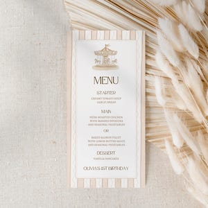 May include: A menu card with a carousel illustration at the top. The menu includes starter, main course, and dessert options. The card has a beige and white striped border and text that reads "Olivia's 1st Birthday."