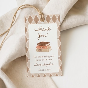 May include: A rectangular paper gift tag with a brown diamond pattern border. The center features the text Thank You! above an illustration of three stacked books, followed by the text for showering our baby with love, Love, Sophia, and 23.10.2026.
