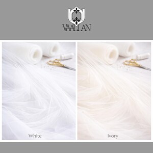 May include: A split-screen display showing white and ivory tulle fabric rolls. Each side features a roll of sheer netting, a small white spool of thread, and gold-toned scissors. The top center displays the Vaallan logo and brand name.