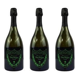 May include: Three green glass champagne bottles with black foil tops. Each bottle has a black and green label with the words "Dom Pérignon Vintage" and a star design. The bottles are arranged in a row.
