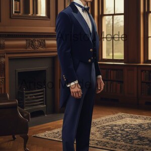 May include: A navy blue formal suit with a velvet tailcoat, vest, and trousers. The suit features gold buttons and a white dress shirt with a bow tie. The setting is a room with a fireplace, bookshelves, and a patterned rug.