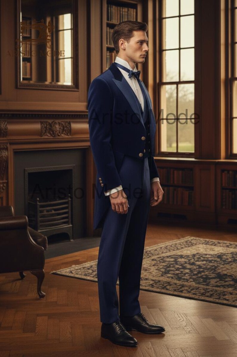 May include: A navy blue formal suit with a velvet tailcoat, vest, and trousers. The suit features gold buttons and a white dress shirt with a bow tie. The setting is a room with a fireplace, bookshelves, and a patterned rug.