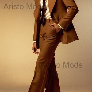 May include: A brown suit with a wide lapel jacket, flared pants, and a patterned tie. The suit is worn over a cream-colored shirt with a large collar. The image has the text "Aristo Mode".