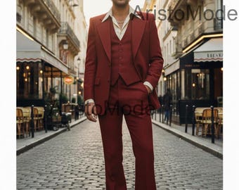 Pode incluir: Um fato bordô de três peças com um casaco de abas largas, um colete e calças de boca de sino. O fato é usado sobre uma camisa creme. A imagem é ambientada numa rua europeia. A marca "AristoMode" é visível.
