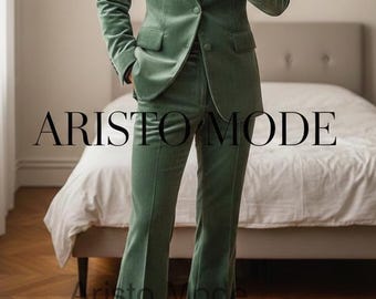 May include: A sage green velvet suit with a single-button closure, notched lapels, and flared pants. The suit features the text "ARISTO MODE" in a bold font. The suit is a stylish ensemble.