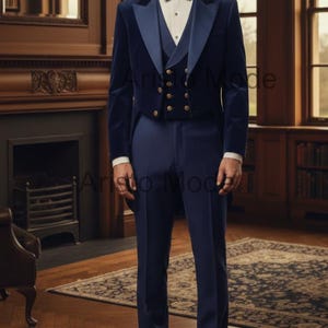 May include: A navy blue formal suit with a velvet jacket, vest, and trousers. The jacket has gold buttons and a contrasting lapel. The suit is paired with a white dress shirt and a navy bow tie. The setting is a room with a fireplace and bookshelves.