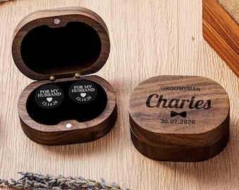 May include: A dark brown wooden box with a hinged lid, open to reveal two black circular inserts engraved with "FOR MY HUSBAND" and a heart icon with the date 12.14.26. A closed matching wooden box is engraved with "GROOMSMAN Charles" and 30.07.2026.