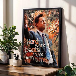 May include: Framed art print featuring a portrait of a man in a suit with the text "Hard work beats talent every time." The artwork has a colorful, abstract background with orange, red, and white accents. The frame is black.