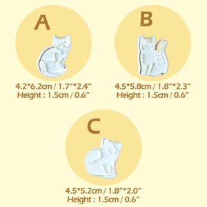 May include: Three white cat-shaped cookie cutters, each inside a tan circle, labelled A, B, and C. Measurements are provided in centimetres and inches. The height of each cutter is 1.5 cm.