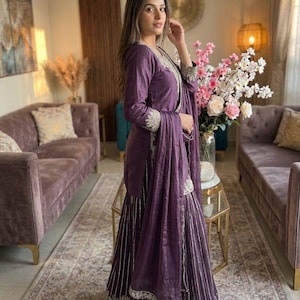 Może przedstawiać: Fioletowy zestaw składający się z topu z długim rękawem i szerokich spodni, ozdobiony srebrnym haftem. Str&oacute;j zawiera pasujący szal. Marka to "Mirzayaa Clothing".