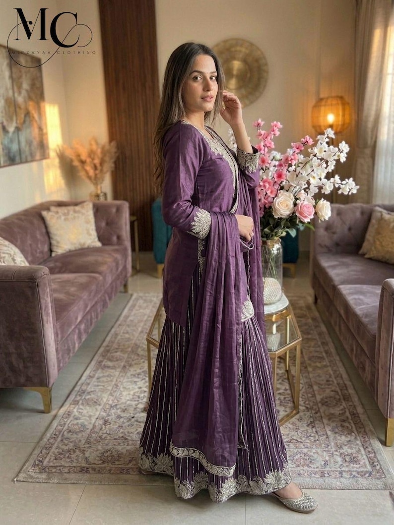 Może przedstawiać: Fioletowy zestaw składający się z topu z długim rękawem i szerokich spodni, ozdobiony srebrnym haftem. Str&oacute;j zawiera pasujący szal. Marka to "Mirzayaa Clothing".