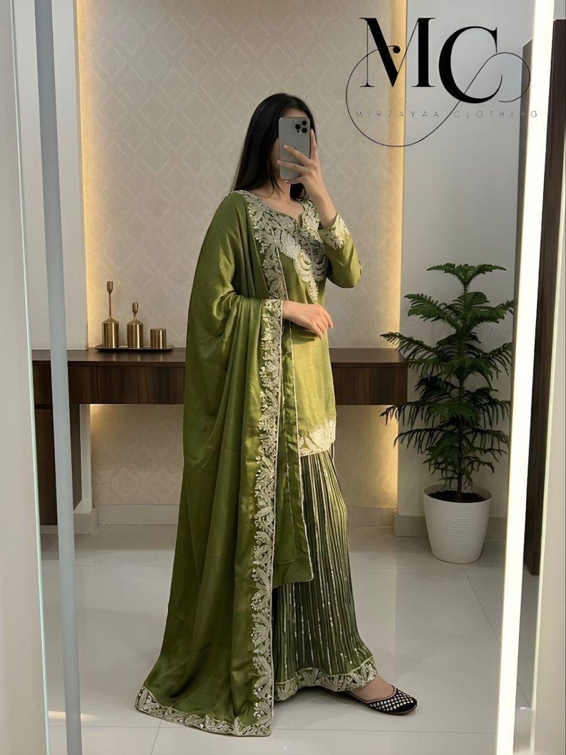 Peut inclure: Ensemble vert olive compos&eacute; d'une tunique &agrave; manches longues, d'un pantalon large et d'un ch&acirc;le assorti. La tenue est orn&eacute;e de broderies complexes sur les bords et les poignets. L'ensemble est fait d'un tissu doux et fluide.