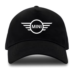 May include: Black baseball cap featuring the white "MINI" logo. The logo is a circle with the word "MINI" inside, flanked by white wings. The cap has a curved brim and a structured crown.