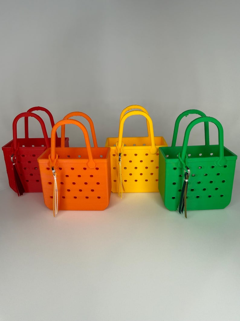 May include: Four colorful tote bags in red, orange, yellow, and green. Each bag has a square shape, a handle, and a tassel. The bags have a perforated design with small, evenly spaced holes.