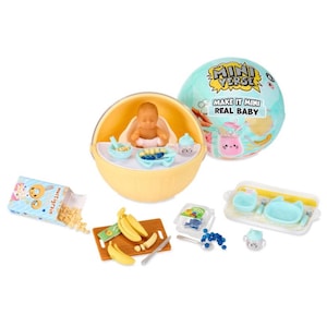 Peut inclure: Un coffret de jeu Mini Verse Real Baby avec une poupée bébé dans un bol jaune, avec des aliments miniatures comme des bananes, des myrtilles et des céréales. L'ensemble comprend une boule bleue et blanche avec le texte "MAKE IT MINI REAL BABY".