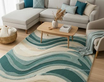 Puede incluir: Salón con un gran sofá seccional gris claro y cojines turquesa y beige. Una mesa de centro de madera descansa sobre una alfombra con un diseño ondulado en tonos turquesa y beige. La alfombra tiene el texto "Rugs Craft Creation".