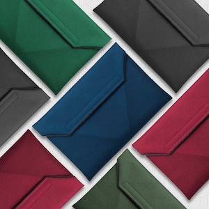 May include: A collection of rectangular laptop sleeves arranged in a geometric pattern. Each sleeve features a flap closure with a stitched horizontal detail and is available in various solid colors including dark green, black, blue, red, and olive.