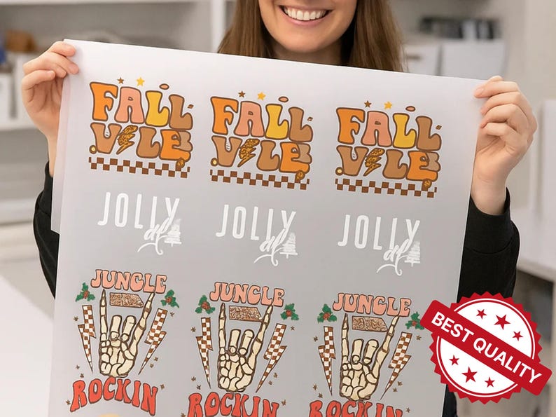 May include: A sheet of printed designs featuring the words "FALL VALE" in orange and brown retro font, "JOLLY", and "JUNGLE ROCKIN" with a skeleton hand graphic. A "BEST QUALITY" sticker is in the bottom right.