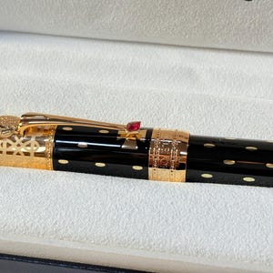 K&ouml;nnte beinhalten: Eine wei&szlig;e Keramik-Tasse mit schwarzem Henkel und dem Text "But First, Coffee" in handschriftlichem Stil. Die Tasse steht auf einer wei&szlig;en Oberfl&auml;che. Die Tasse ist etwa 10 cm hoch.