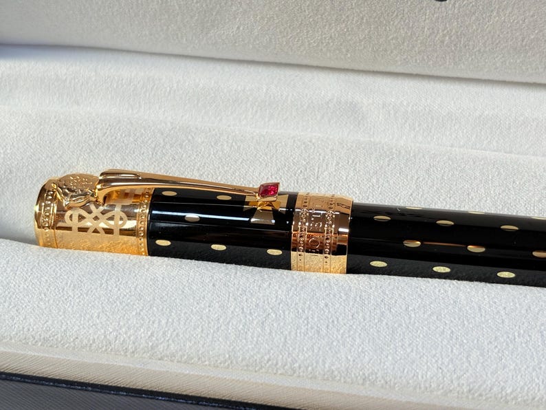 K&ouml;nnte beinhalten: Eine wei&szlig;e Keramik-Tasse mit schwarzem Henkel und dem Text "But First, Coffee" in handschriftlichem Stil. Die Tasse steht auf einer wei&szlig;en Oberfl&auml;che. Die Tasse ist etwa 10 cm hoch.