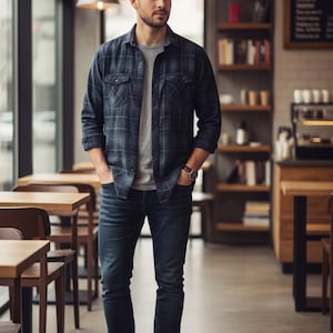 Può includere: Una persona indossa una camicia a quadri blu sopra una maglietta grigia, jeans blu scuro e stivali di pelle marrone. La persona si trova in un bar con tavoli e sedie di legno.