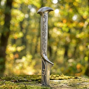 Könnte beinhalten: Ein Brieföffner aus silberfarbenem Metall mit einem länglichen Griff, einem geschwungenen Ende und detaillierten Rankengravuren. Der Klingenbereich zeigt ein ausgeschnittenes Schnörkelmuster, das ein dekoratives und funktionales Schreibtischaccessoire bildet.