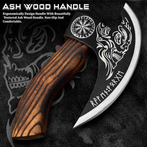 Könnte beinhalten: Eine schwarze und silberne Axt mit gebogener Klinge und Holzgriff. Die Klinge zeigt ein Totenkopf-Design und Runen. Der Griff ist aus Eschenholz. Der Text "ASH WOOD HANDLE" ist sichtbar.