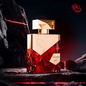 May include: A perfume bottle with a gold cap and accents, and a faceted red glass body. The bottle is labeled "UTOPIA opal" and sits on a dark, textured surface. The background features dark rock formations.