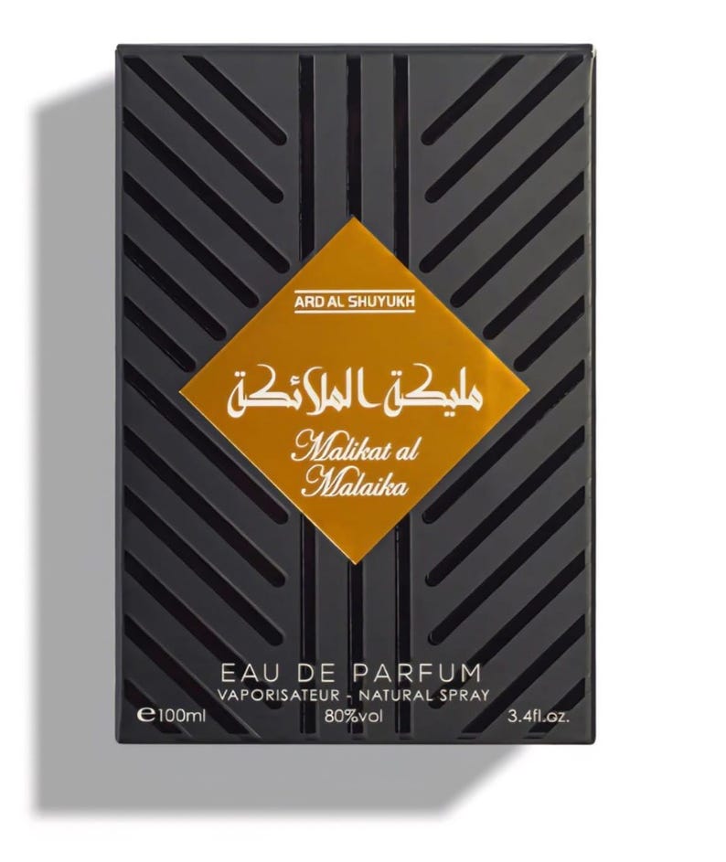 May include: Black rectangular perfume box with diagonal lines and a gold diamond-shaped label. The label features Arabic and English text: "Malikat al Malaika". The box also indicates "EAU DE PARFUM" and 3.4 fl.oz.