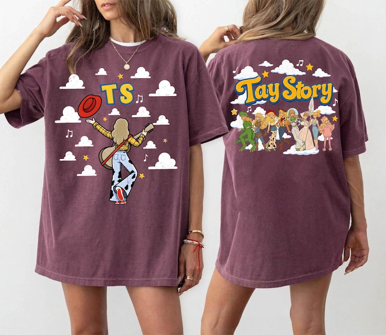 May include: A maroon short-sleeve t-shirt featuring a graphic print. The front displays the text TS with a figure holding a guitar and hat against a cloud background. The back shows a group of figures with the text Tay Story and clouds.