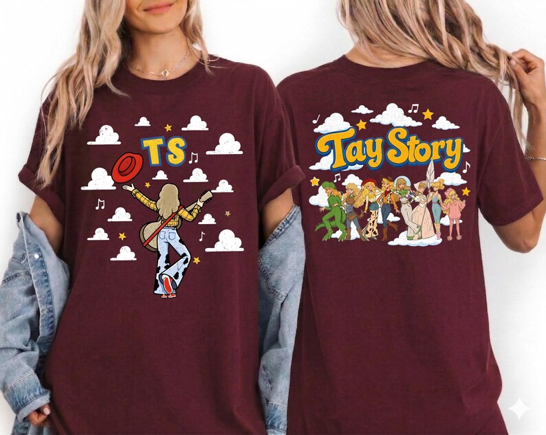 May include: A maroon t-shirt featuring a graphic print. The front displays a figure with a guitar, a red hat, and the text TS against a sky with clouds. The back shows a group of illustrated characters and the text Tay Story with clouds.
