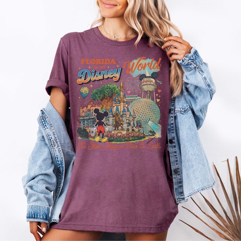May include: A purple short-sleeve t-shirt featuring a graphic print of Florida Disney World. The design includes Mickey Mouse, the castle, the Epcot sphere, the Hollywood Tower, and the text Florida Disney World The Most Magical Place On Earth.