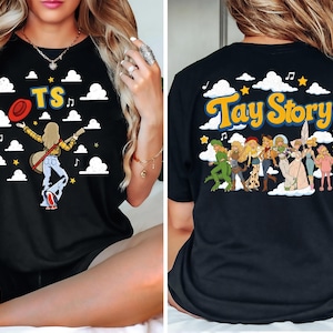 May include: A black t-shirt featuring a front graphic of a person with a guitar and the letters TS, and a back graphic with the text Tay Story above a group of illustrated characters in various outfits, all set against a background of white clouds.