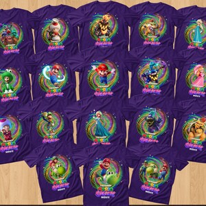 May include: A collection of purple t-shirts featuring various characters from The Super Mario Bros. Movie, including Mario, Luigi, Peach, Toad, and Bowser, each centered within a colorful, swirling cosmic graphic with the movie title text.