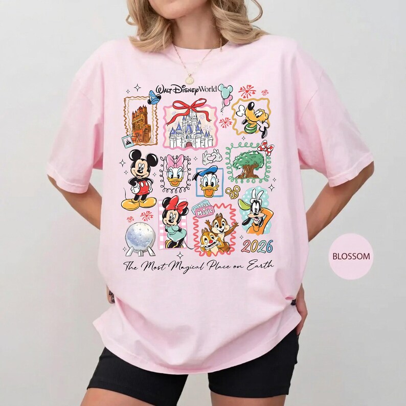 Może przedstawiać: Jasnor&oacute;żowa koszulka z kolorową grafiką przedstawiającą r&oacute;żne postacie i zabytki Disneya. Widoczny jest napis "Walt Disney World" i "The Most Magical Place on Earth". Widoczny jest r&oacute;wnież rok "2026".