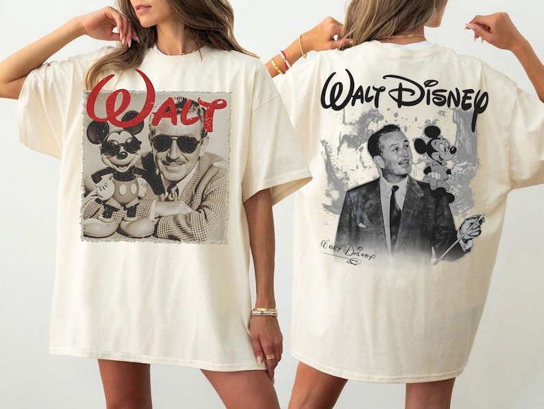 May include: An off-white t-shirt featuring a front graphic of Walt Disney and Mickey Mouse with the red text "Walt" above them. The back graphic displays Walt Disney and Mickey Mouse with the black text "Walt Disney" printed above.