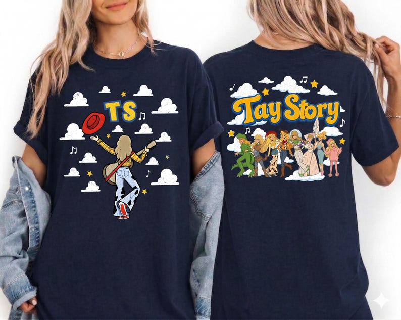May include: A navy blue t-shirt featuring a graphic print on the front and back. The front shows a figure with a guitar and the text TS. The back displays a group of characters and the text Tay Story, both set against a background of clouds.
