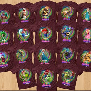 May include: A collection of maroon short-sleeved t-shirts, each featuring a unique graphic print of characters from The Super Mario Bros. Movie. The designs are centered within a swirling, colorful cosmic background and include the movie title text.