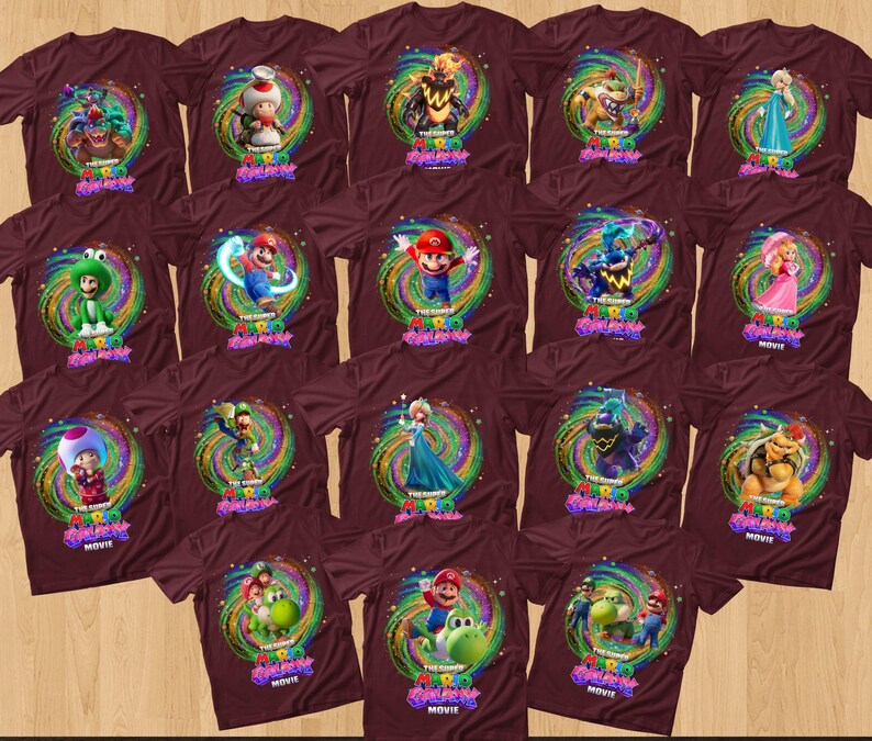 May include: A collection of maroon short-sleeved t-shirts, each featuring a unique graphic print of characters from The Super Mario Bros. Movie. The designs are centered within a swirling, colorful cosmic background and include the movie title text.