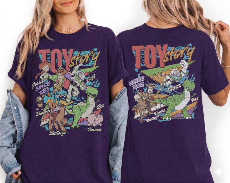 May include: A dark purple t-shirt featuring a graphic print of Toy Story characters including Jessie, Woody, Buzz Lightyear, Rex, Slinky Dog, Bullseye, and Hamm. The design includes the text Toy Story and Since 1995 with colorful geometric shapes.