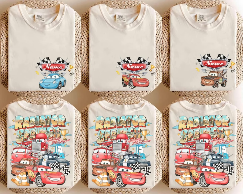Puede incluir: Una colecci&oacute;n de camisetas color crema con estampados gr&aacute;ficos. La fila superior muestra personajes de coches individuales con banderas a cuadros y el texto Name. La fila inferior muestra un gran gr&aacute;fico de Radiator Springs con varios coches.