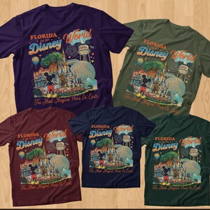 May include: Five short-sleeved t-shirts in purple, olive green, maroon, navy blue, and dark green. Each shirt features a graphic print of Florida Disney World with Mickey Mouse, the castle, and the text The Most Magical Place On Earth.