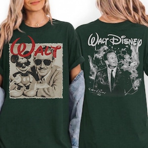 May include: A dark green t-shirt featuring a front graphic of Walt Disney and Mickey Mouse wearing sunglasses with the red text "WALT" above them. The back of the shirt displays a black and white portrait of Walt Disney with the text "Walt Disney".