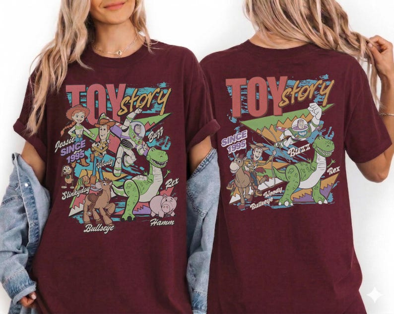 May include: A maroon short-sleeve t-shirt featuring a graphic print of Toy Story characters including Jessie, Woody, Buzz Lightyear, Rex, Slinky Dog, Bullseye, and Hamm. The text reads Toy Story and Since 1995, with character names printed below.