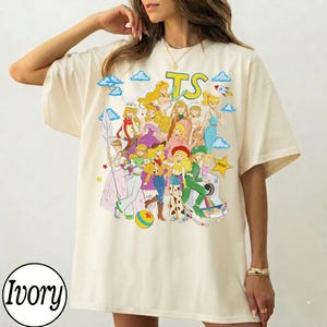Puede incluir: Una camiseta de manga corta color marfil con un estampado gr&aacute;fico colorido de varios personajes animados con diversos atuendos. El dise&ntilde;o incluye las letras TS en la parte superior, una estrella amarilla, un cohete y nubes azules en collage.
