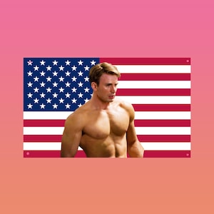 May include: A shirtless person stands in front of an American flag. The flag features red and white stripes and a blue field with white stars. The background is a gradient of pink and orange.