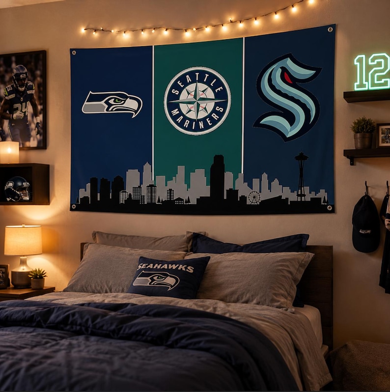 Puede incluir: Un tapiz de pared rectangular con tem&aacute;tica deportiva de Seattle, con un dise&ntilde;o de paneles verticales en azul oscuro, verde azulado y azul oscuro. Muestra el logotipo de los Seattle Seahawks, el logotipo de la br&uacute;jula de los Seattle Mariners y el logotipo del Seattle Kraken sobre un horizonte urbano negro.
